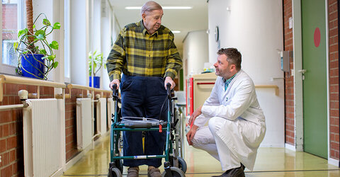 Arzt der KRH Geriatrie Langenhagen hilft Patienten mit Rollator.